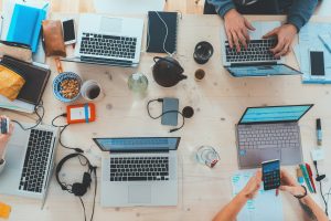 Image of laptops on a table and someone holding a mobile